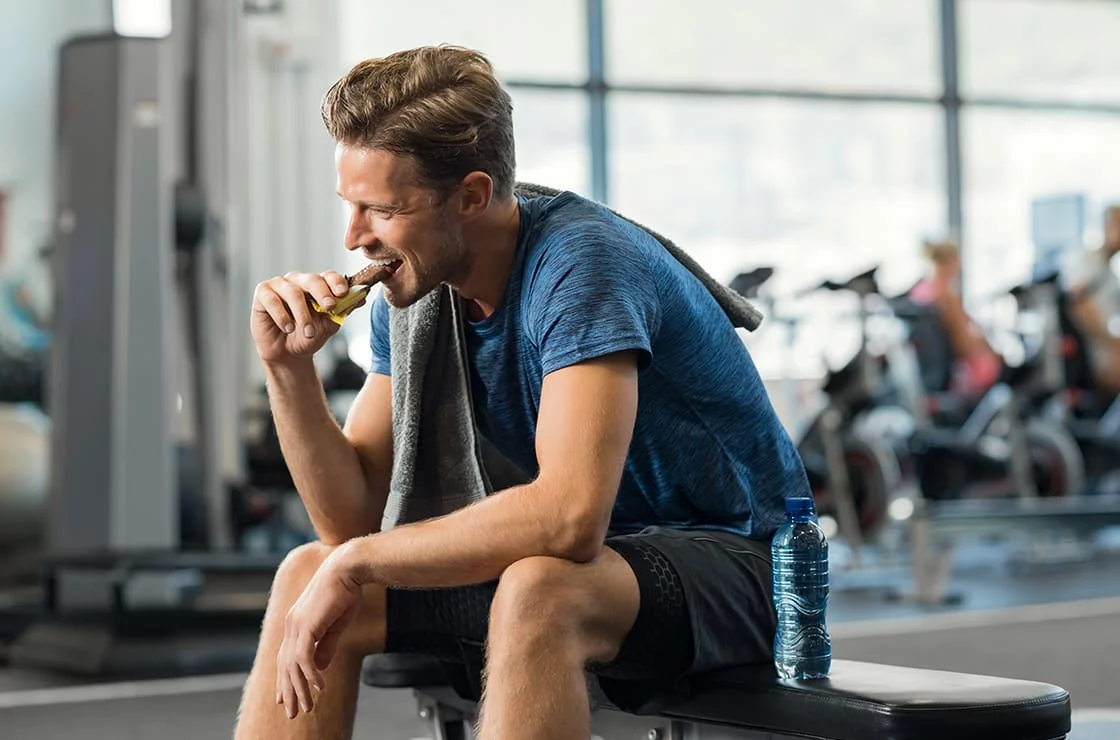 Deportista comiendo una barrita tras entrenar en el gimnasio